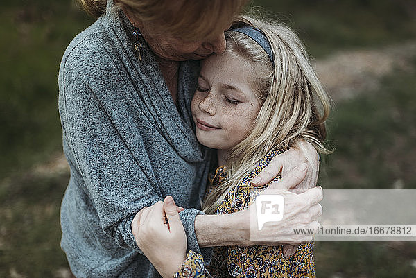 Detailaufnahme eines jungen Mädchens  das von einer älteren Großmutter umarmt wird