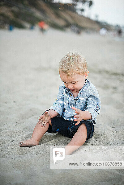 Kleiner Junge spielt mit Sand an einem kalifornischen Strand