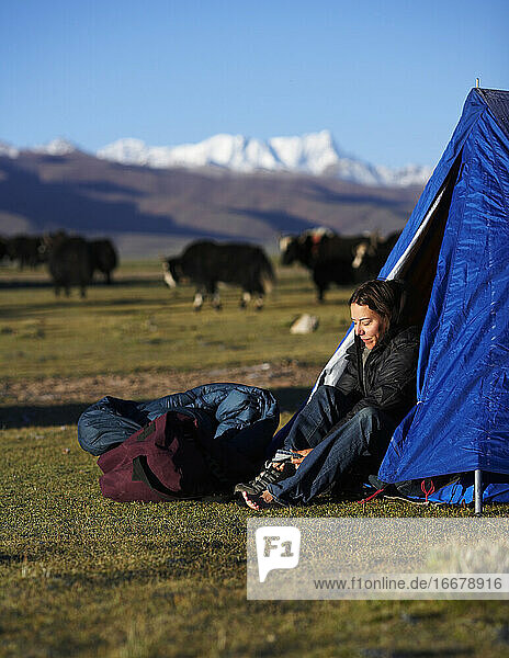 woman putting her boots on at camp in Tibet