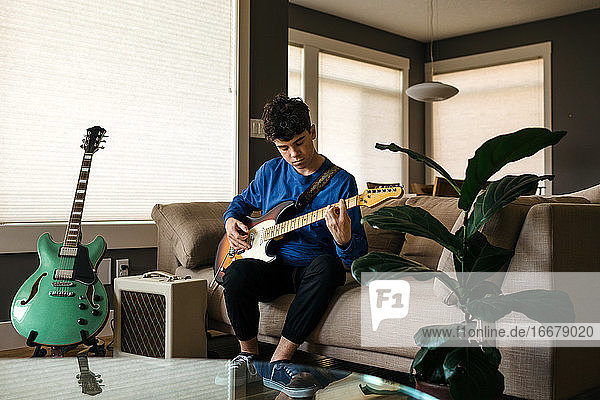 Teenager playing the guitar at home