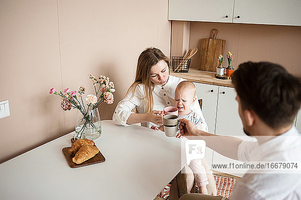 Eltern trösten ein weinendes Kind in der modernen Küche. Familienroutinen