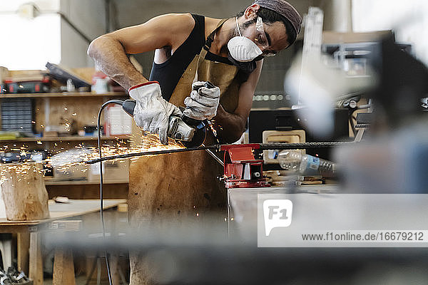 Männlicher Arbeiter schneidet Metall in einer Werkstatt