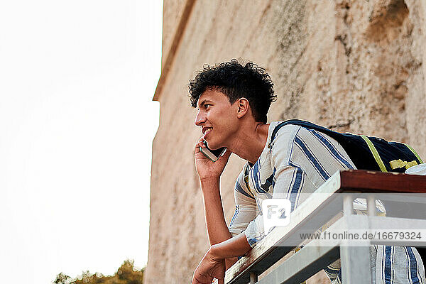 Junger Mann mit Afro-Haar benutzt sein Smartphone im Freien