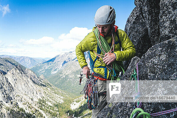Mann sortiert beim Klettern in Washington seine Ausrüstung am Klettergurt