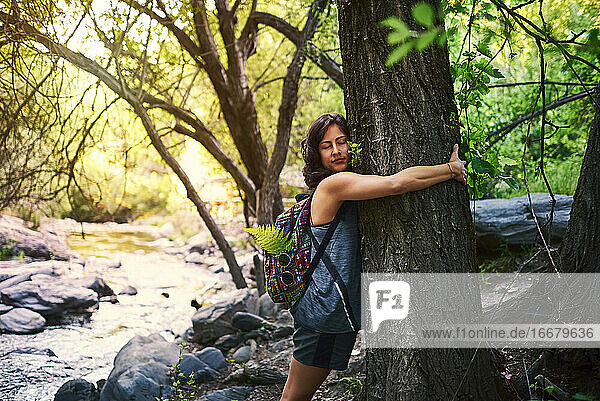 Junge Frau  die einen Baum umarmt. Sie ist glücklich.