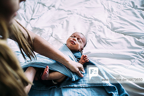 Overhead-Aufnahme eines neugeborenen Babys  das in eine Decke eingewickelt wird