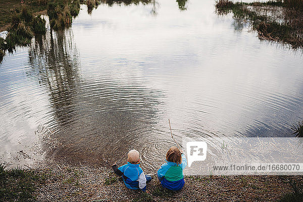 Rückenansicht von jungen Kindern vor einem See in einem Park an einem bewölkten Tag