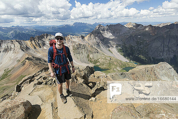 Smiling male hiker standing on rocky mountain