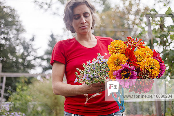 eine Gärtnerin hält einen bunten Strauß Wildblumen in die Höhe
