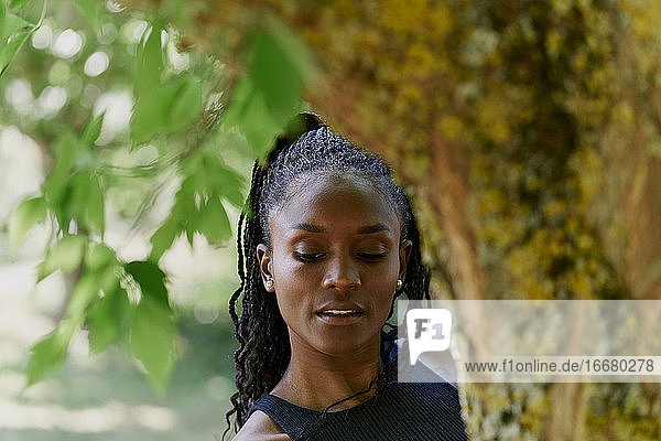 Porträt einer schönen schwarzen Frau hinter einem Baum
