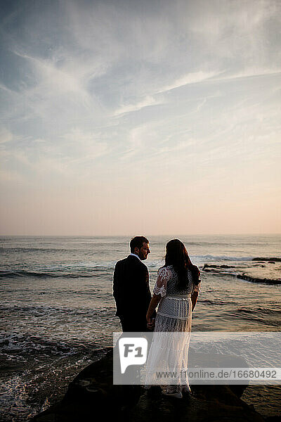 Newlyweds Standing on Rock at Beach in San Diego During Sunset