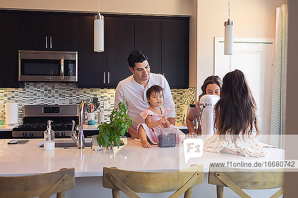 Rückenansicht einer jungen vierköpfigen Familie beim gemeinsamen Backen in der Küche.