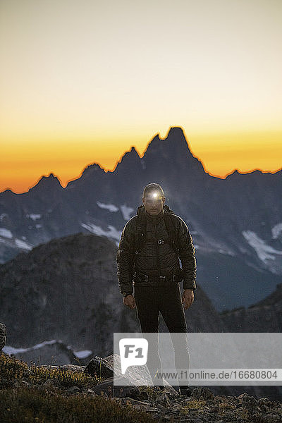 Backpacker hikes with headlamp on at dusk.