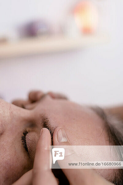 Weibliche Masseurin massiert die Augenbrauen eines männlichen Patienten