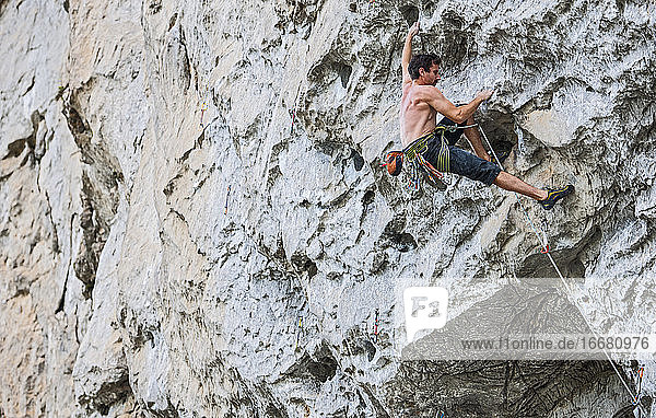 junger Mann beim Klettern auf einen Überhang in Yangshuo / China