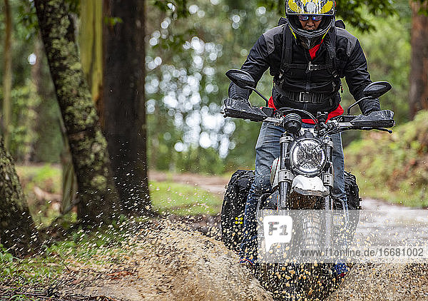 Mann fährt mit seinem Scrambler-Motorrad durch den Wald