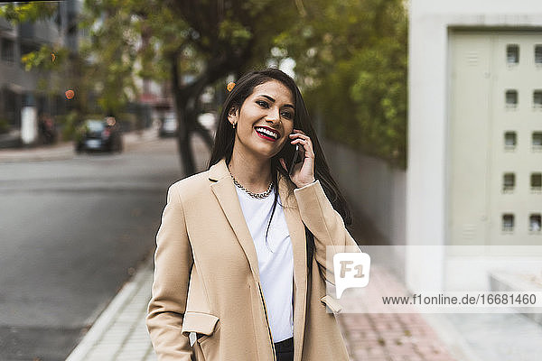 schöne hispanische Frau  die auf der Straße telefoniert