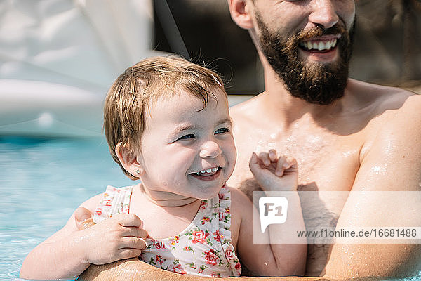 Selektiver Fokus auf ein lächelndes Mädchen  das sich mit dem Gesicht im Wasser dreht und einen Mann umarmt