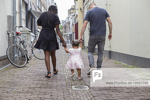 Ein junges Paar geht mit seiner Tochter spazieren