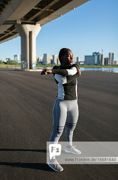Afroamerikanische Sportlerin beim Aufwärmen unter einer Brücke