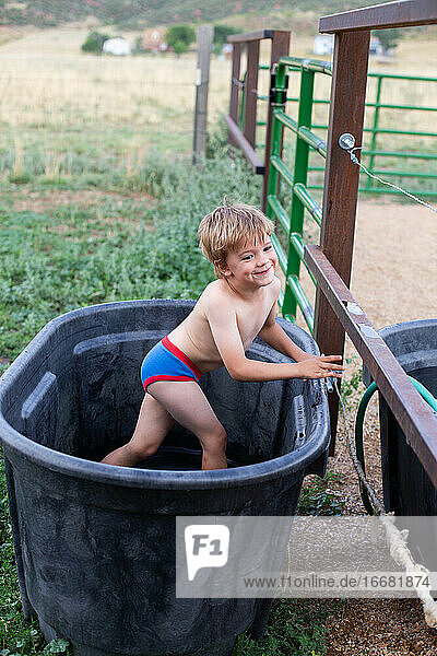 Junge  der im Sommer in seiner Unterwäsche in einer Pferdetränke spielt