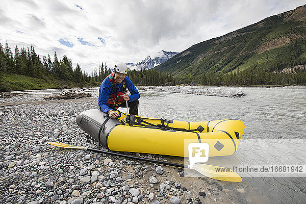 Paddler bläst gelbes Packraft am North Saskatchewan River auf.