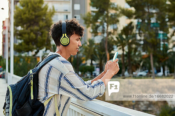 Young afro-haired man is using his smartphone and listening to music