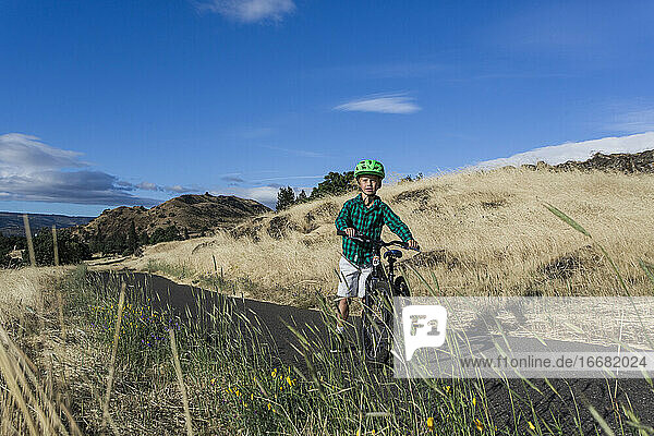 A young boy rides his bike with his mom in the Columbia Gorge.