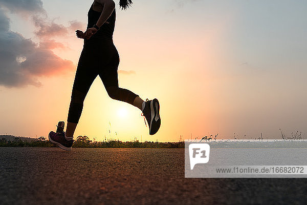 Sport Frau läuft auf einer Straße. Fitness Frau Training bei Sonnenuntergang