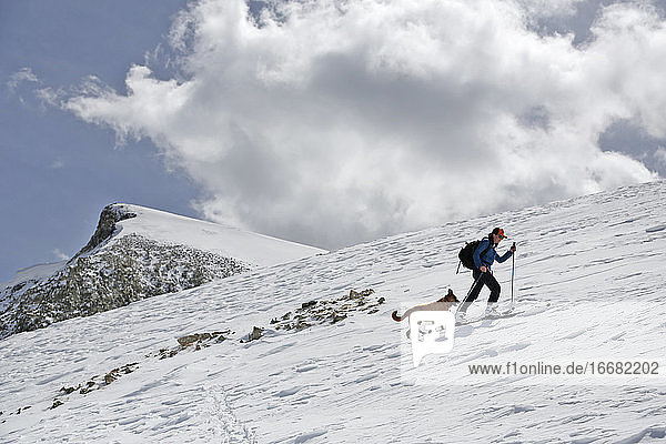 Eine Frau erklimmt an einem sonnigen Tag in Colorado mit ihrem Hund den Mount Sopris.