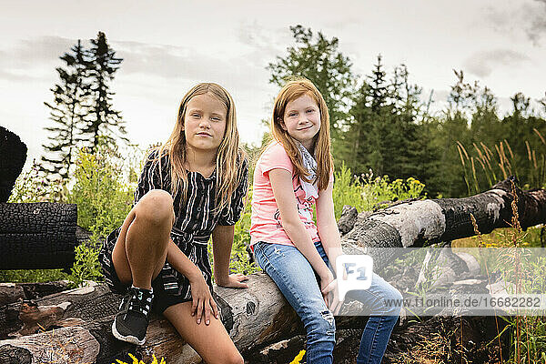 Two Young Girls Sitting on a Log