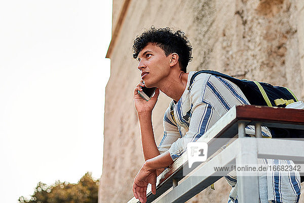 Junger Mann mit Afrohaar benutzt sein Smartphone im Freien