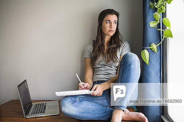 Einsame einzelne Frau Auf ihrem Laptop arbeiten / studieren zu Hause