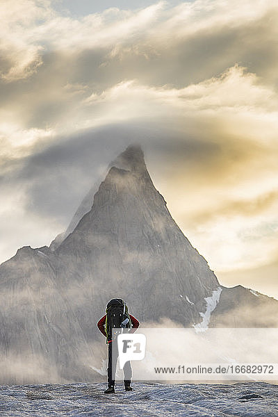 Climber standing in front of Mt. Loki  Baffin Island  Canada.