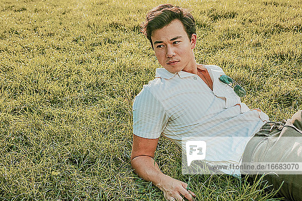 Portrait of a young man sitting on grass.