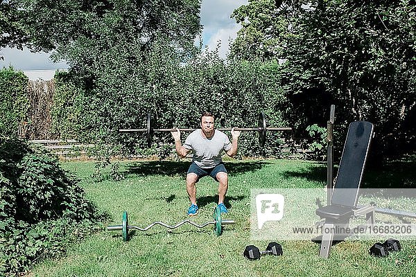 man working out at home in the garden with his home gym equipment