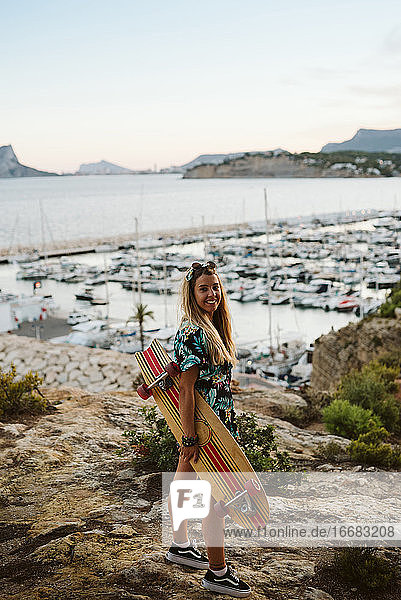 Junge Frau mit langem Brett skatet vor dem Yachtclub von Moraira