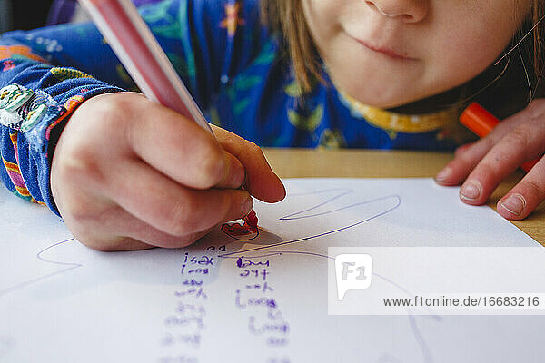 Nahaufnahme eines kleinen Mädchens  das mit einem bunten Marker auf Papier zeichnet