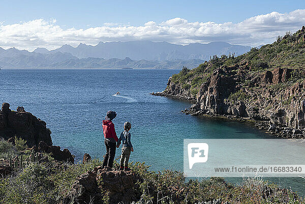 A woman and her son standing on a rock at a beach in Del Carmen Island