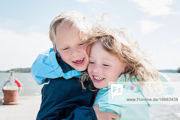 portrait of brother and sister laughing at the beach together