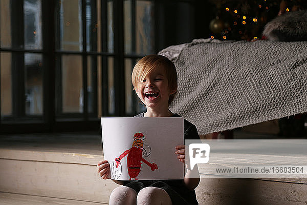 Ein fröhliches Mädchen hat den Weihnachtsmann gemalt.