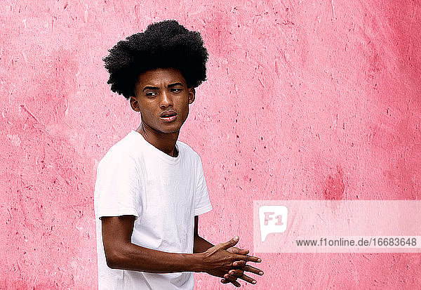 attraktiver junger schwarzer mann schlendert vor einer rosa wand  kuba