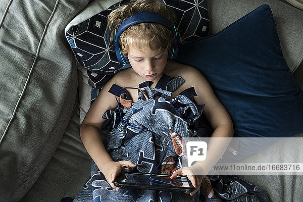 Draufsicht auf einen jungen Jungen mit Kopfhörern auf einem Tablet-Computer