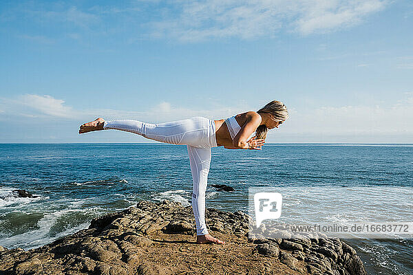 Junge Frau übt Yoga am Strand