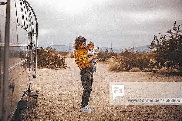 Eine Frau mit einem Baby steht in der Nähe eines Wohnmobil-Anhängers  Joshua Tree  Kalifornien