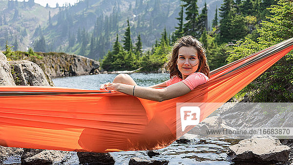 Frau entspannt sich in einer Hängematte am Alpensee im Urlaub vor Ort