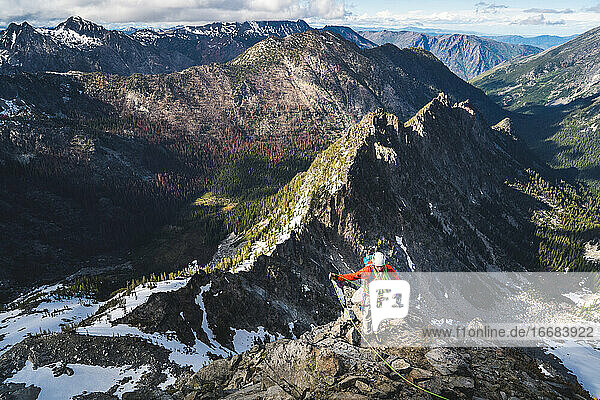 Mann wickelt Seil beim Klettern mit hohen Bergen im Hintergrund