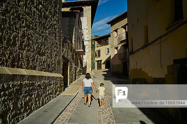 Mutter und Tochter spazieren in einer Gasse mit alten Häusern in Mora