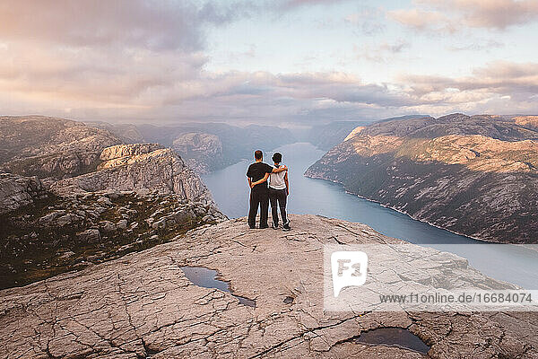 Couple standing at cliff at Preikestolen  Norway during sunset