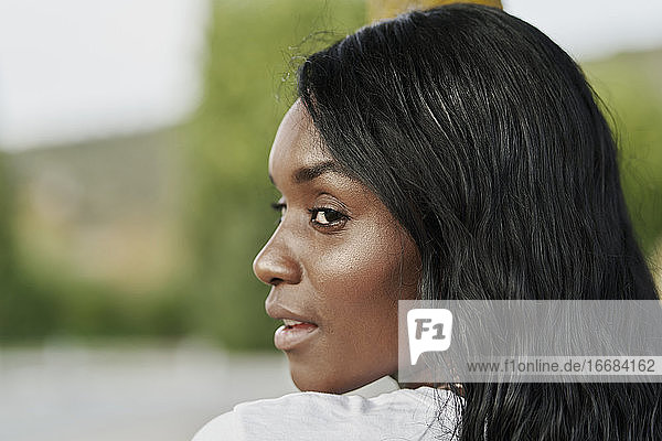 Schöne schwarze Frau schaut zur Seite in einem Park